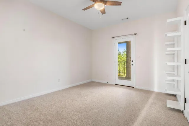 an empty room with windows and ceiling fan