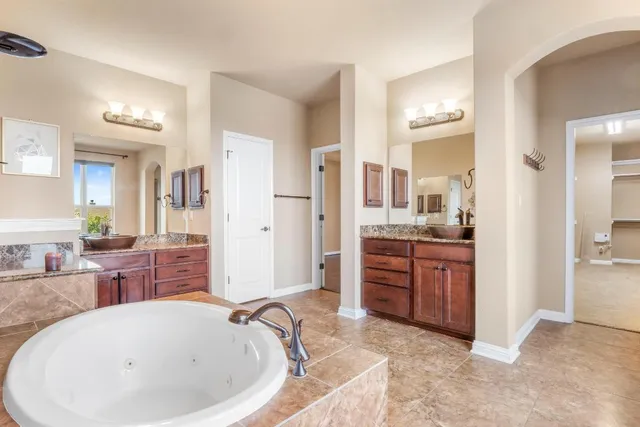 a bathroom with a tub a sink and a large mirror