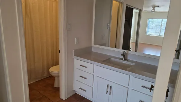 a bathroom with a granite countertop sink toilet and mirror
