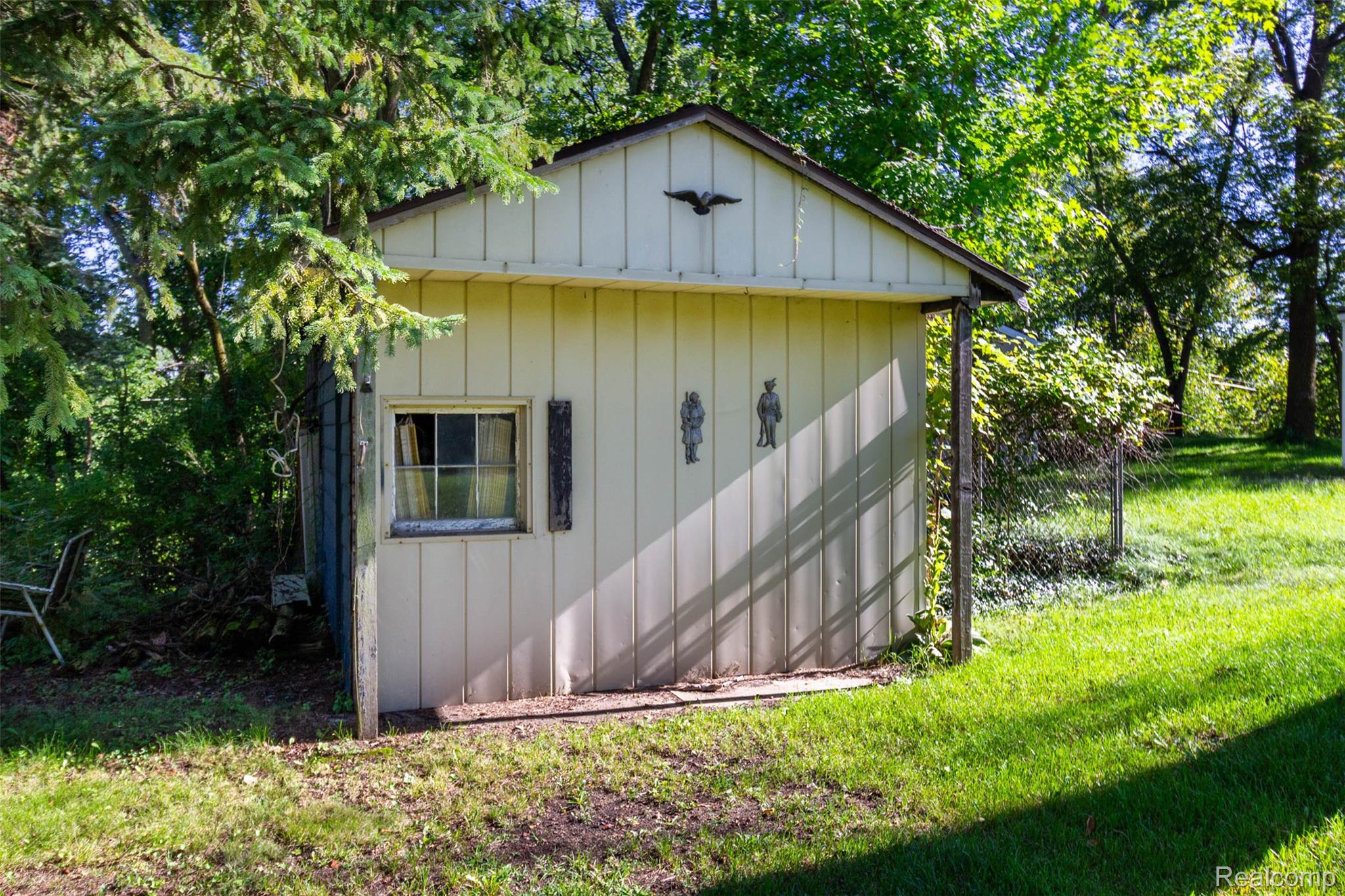 14044 Ridgemont Drive Gregory, MI 48137 - Photo 28 of 33 Gabled outbuilding with vertical siding, a single window, and mature surrounding trees