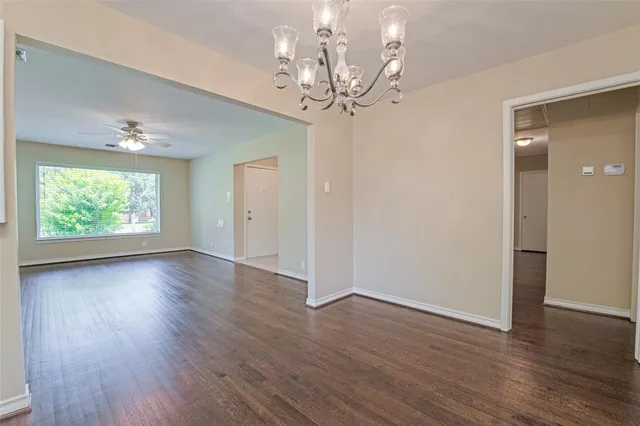a view of a room with wooden floor chandelier and windows
