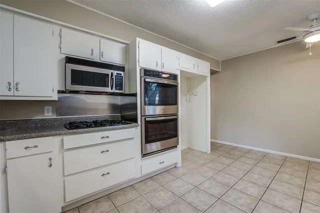a kitchen with granite countertop white cabinets a oven a sink and dishwasher
