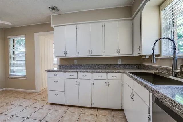 a kitchen with granite countertop white cabinets and sink
