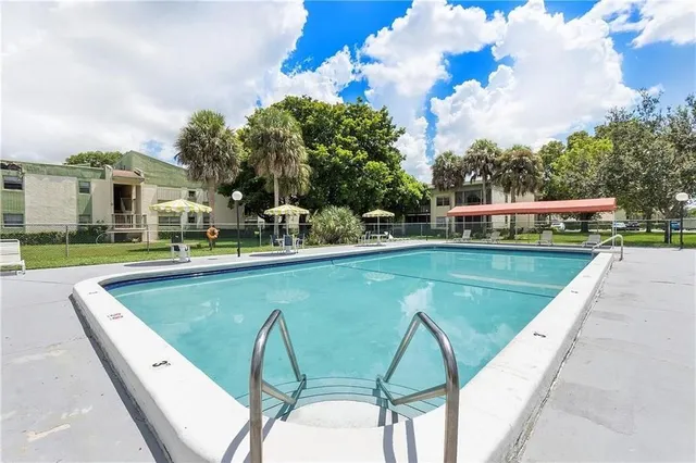 a view of swimming pool with outdoor seating and trees in the background