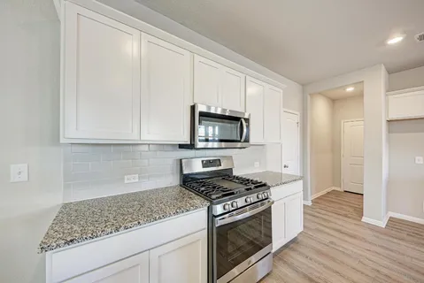 a large kitchen with stainless steel appliances granite countertop a lot of counter space and wooden floor