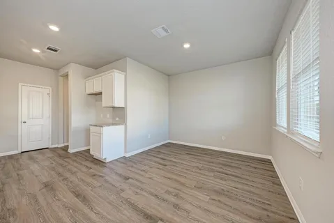 an empty room with wooden floor and cabinet