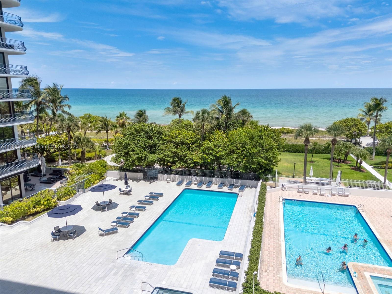 8877 Collins Avenue, Unit 303 Surfside, FL 33154 - Photo 24 of 25 a view of a swimming pool with a lawn chairs potted plants