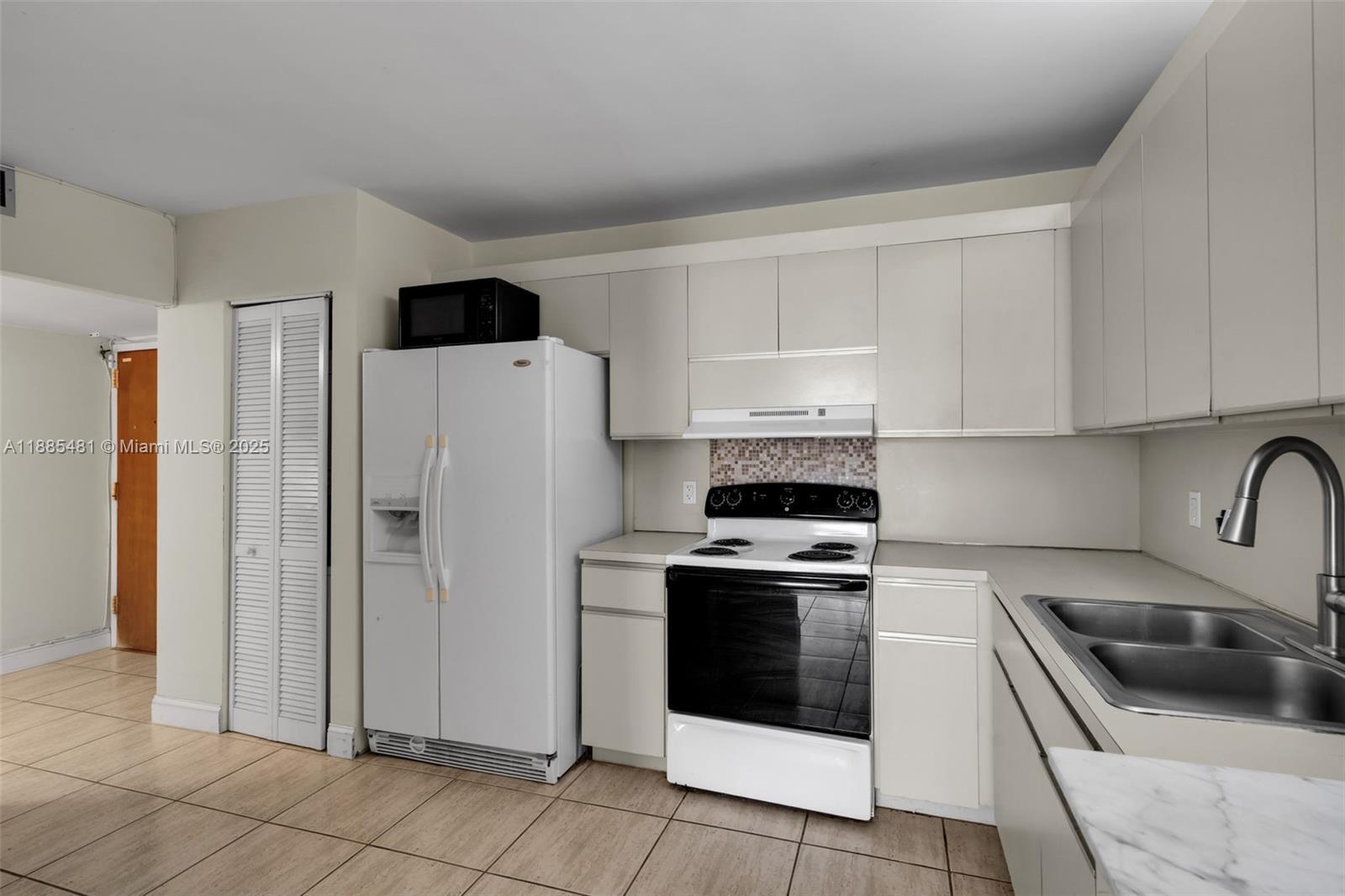 8877 Collins Avenue, Unit 303 Surfside, FL 33154 - Photo 9 of 25 a kitchen with a refrigerator sink and stove