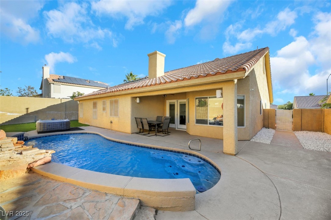 Rear view of property with french doors, a pool, a fenced backyard, patio, and stucco siding