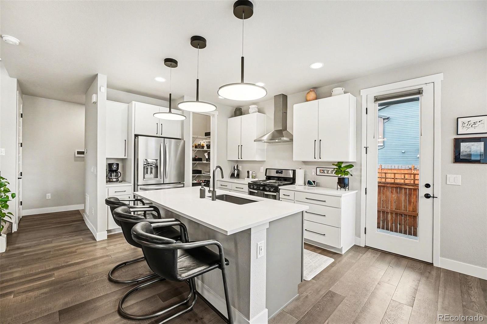 6793 Canosa Street Denver, CO 80221 - Photo 11 of 34 a kitchen with stainless steel appliances a dining table chairs stove and refrigerator
