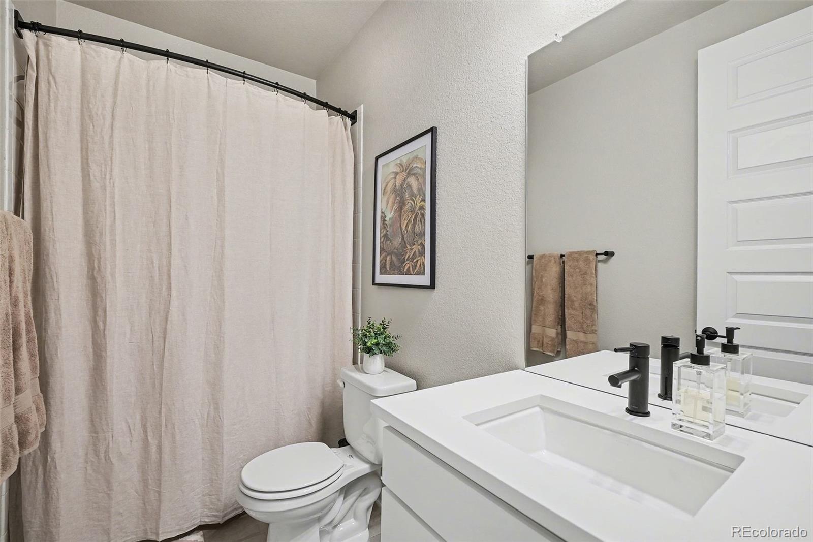 6793 Canosa Street Denver, CO 80221 - Photo 17 of 34 a bathroom with a sink a toilet and a mirror