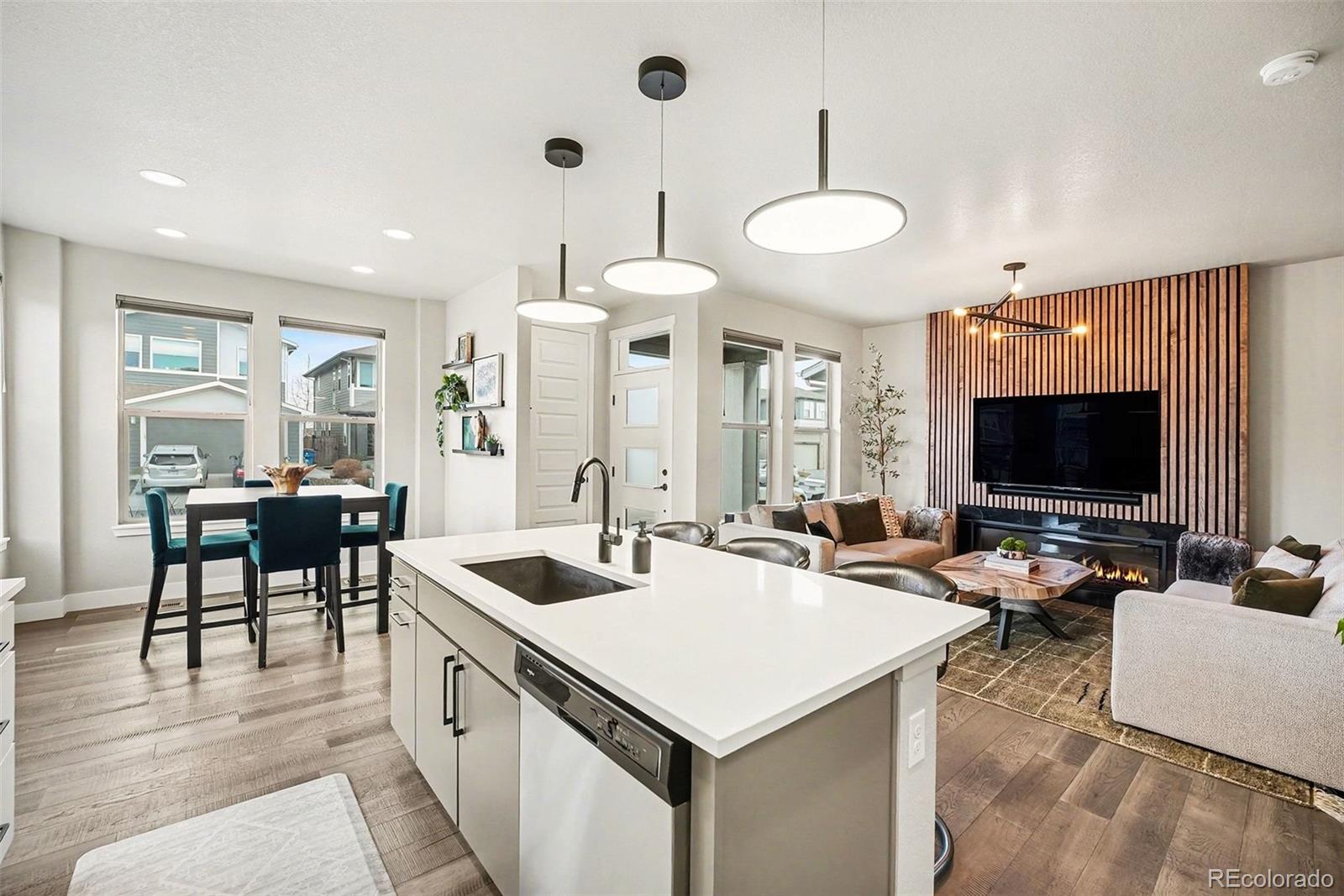 6793 Canosa Street Denver, CO 80221 - Photo 8 of 34 a kitchen with a stove a kitchen island a couches and a flat screen tv