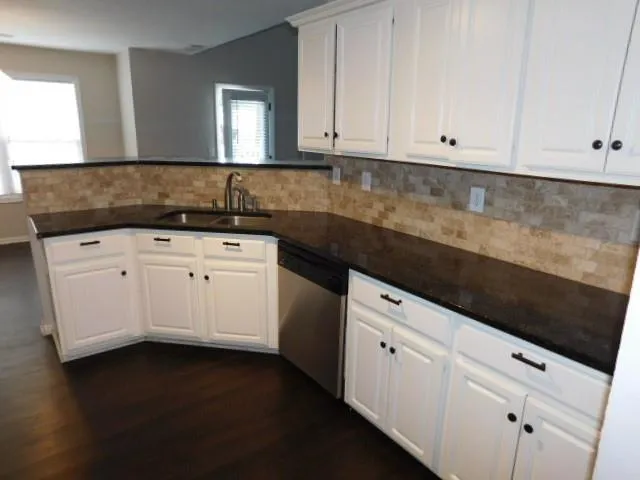 a kitchen with granite countertop white cabinets and sink