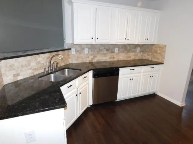 a kitchen with granite countertop white cabinets and sink
