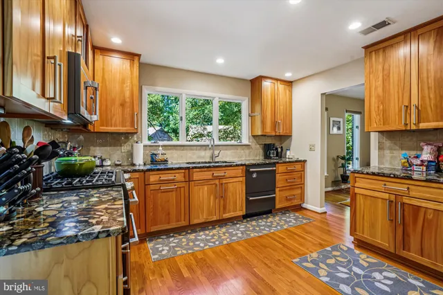 a kitchen with stainless steel appliances granite countertop a stove top oven a sink dishwasher a microwave oven with granite countertops and cabinets