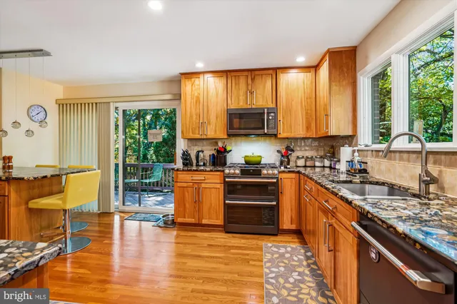 a large kitchen with granite countertop a stove a sink and a refrigerator