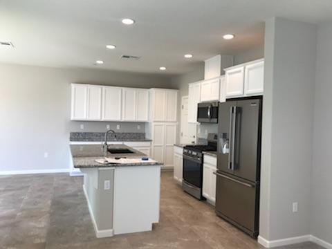 21113 Pinot Noir Drive Patterson, CA 95363 - Photo 3 of 5 a kitchen with stainless steel appliances granite countertop a stove top oven a refrigerator and a sink