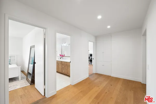 a view of a hallway with bathroom and wooden floor