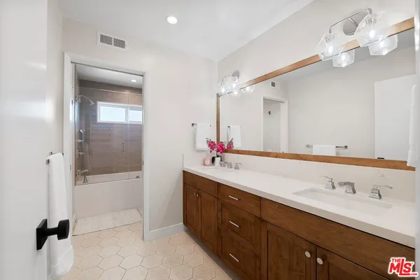 a bathroom with a double vanity sink mirror and shower