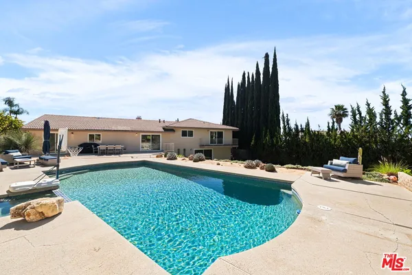 a view of a swimming pool and lounge chairs in patio