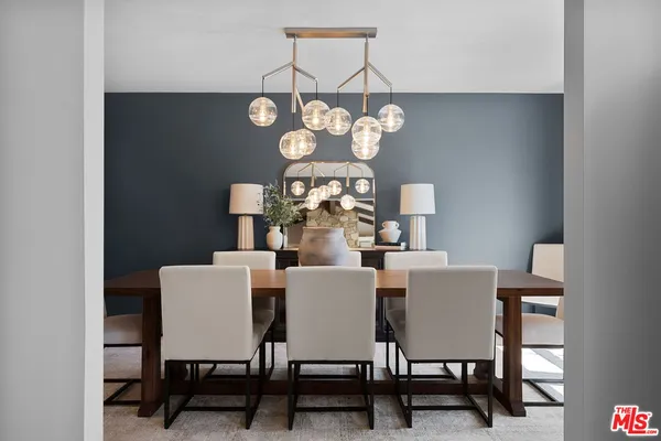 a dining room with wooden floor a chandelier a wooden table and chairs