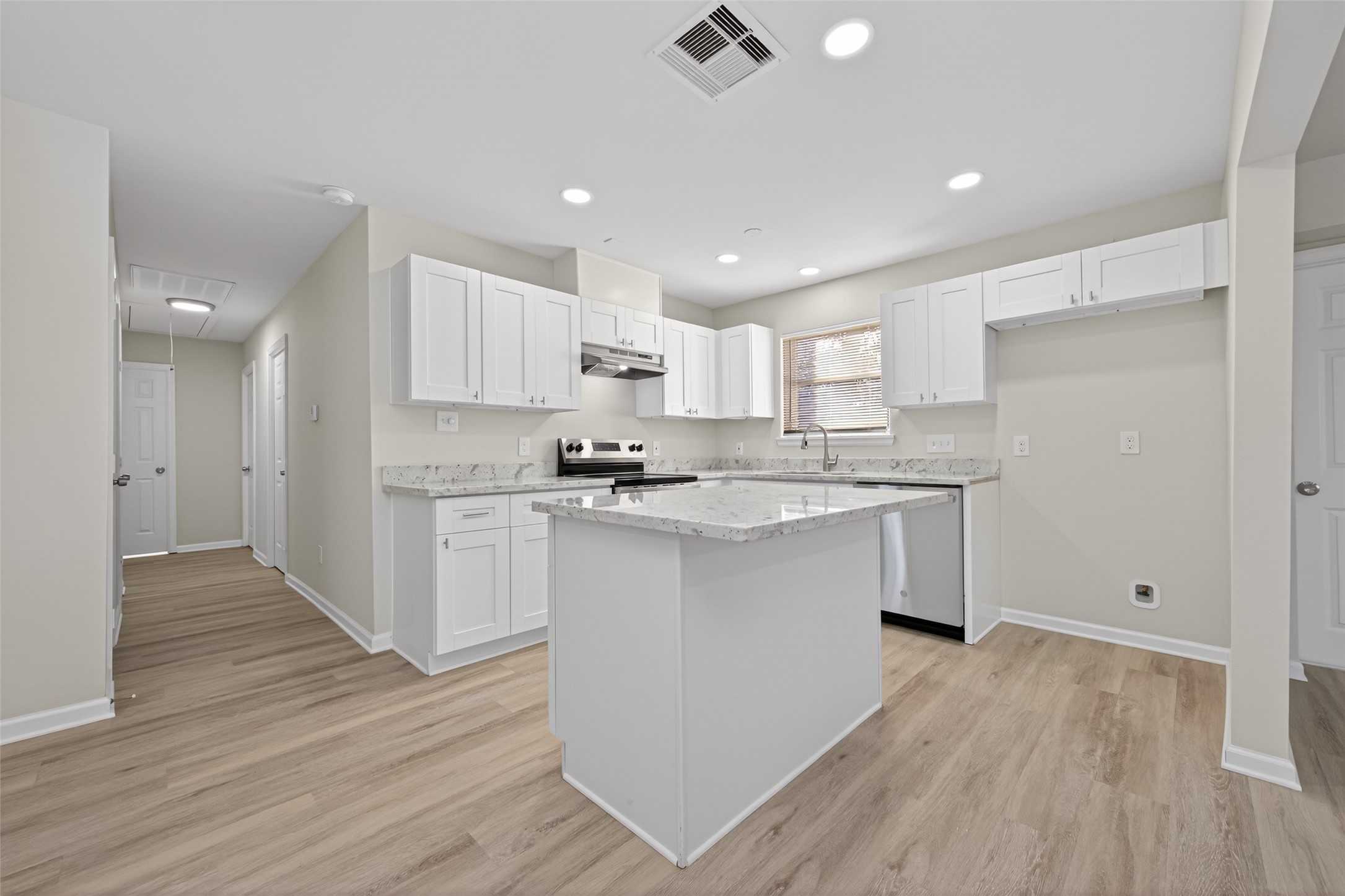 1238 Hopper Road Houston, TX 77037 - Photo 7 of 40 a kitchen with a refrigerator a stove top oven a sink and white cabinets with wooden floor