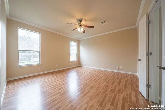 a view of empty room with wooden floor and fan