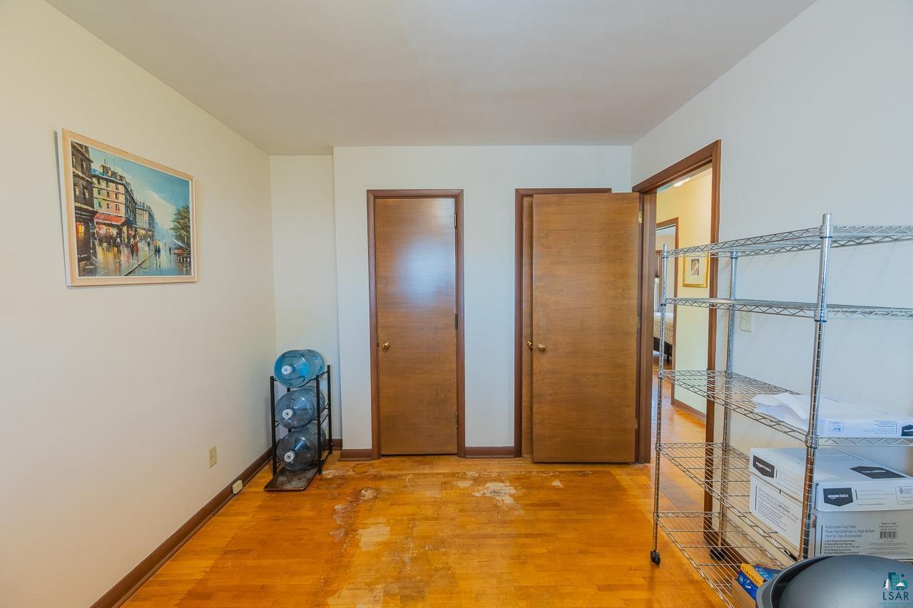 101 2nd Avenue North Biwabik, MN 55708 - Photo 20 of 44 Wood-finish flooring with visible wear, two paneled doors, and a doorway opening to an interior space