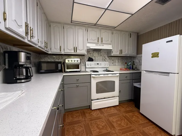 a kitchen with stainless steel appliances granite countertop a refrigerator a stove a sink dishwasher and white cabinets with wooden floor