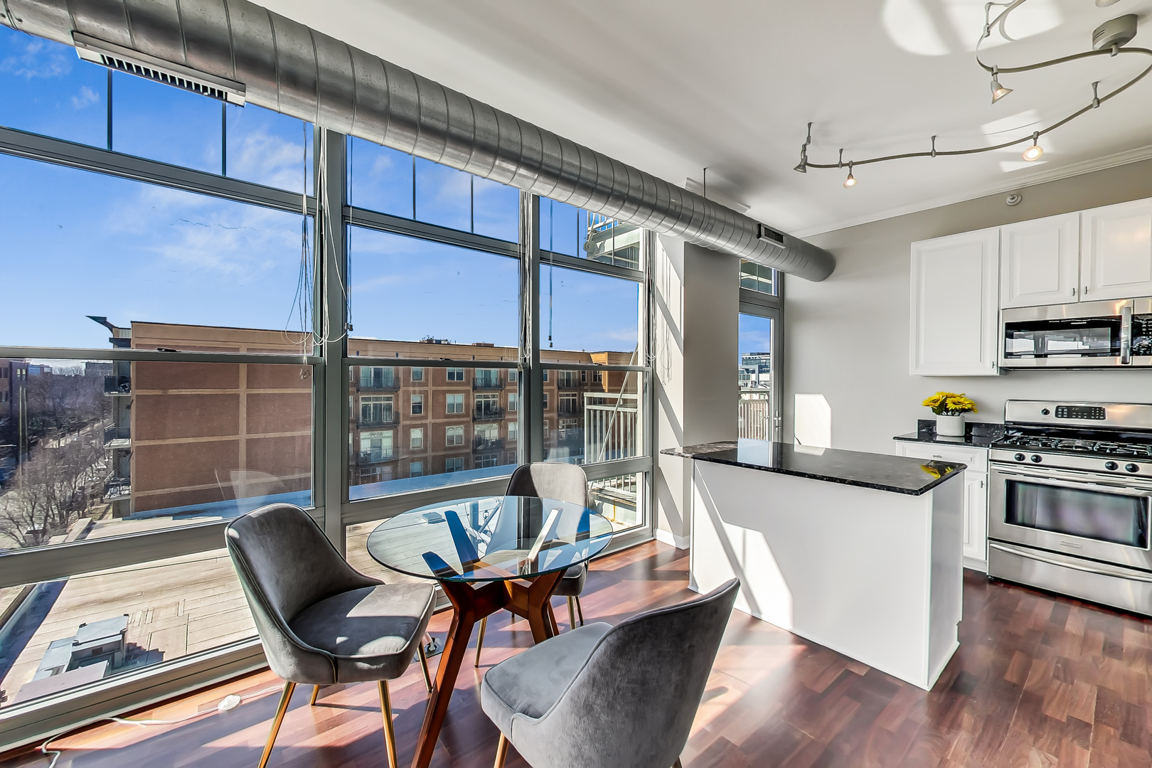 1200 West Monroe Street, Unit 511 Chicago, IL 60607 - Photo 4 of 12 a kitchen with stainless steel appliances granite countertop a stove top oven a dining table and chairs with wooden floor
