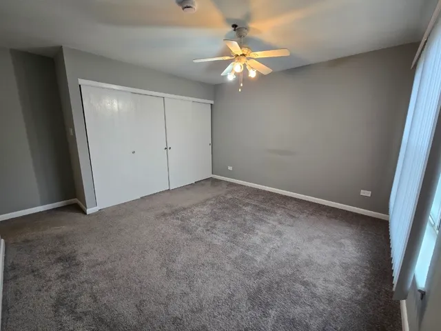 an empty room with chandelier fan and windows