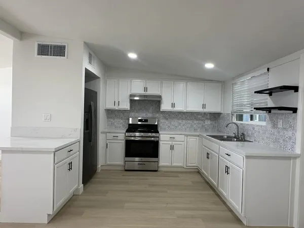 a kitchen with stainless steel appliances granite countertop a stove a sink and a refrigerator