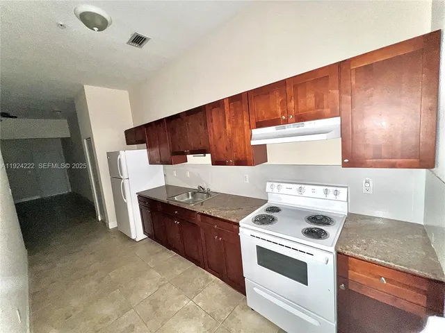 a kitchen with stainless steel appliances granite countertop a stove a sink and a refrigerator