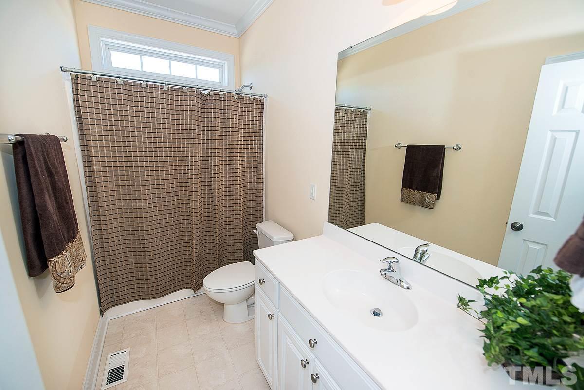 5005 Contender Drive Raleigh, NC 27603 - Photo 14 of 21 a bathroom with a sink a toilet a mirror and shower curtain