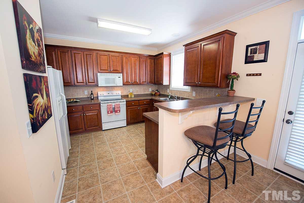 5005 Contender Drive Raleigh, NC 27603 - Photo 7 of 21 a kitchen with stainless steel appliances granite countertop a stove top oven a sink a dining table and chairs with wooden floor