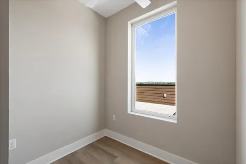 a view of an empty room with wooden floor and a window