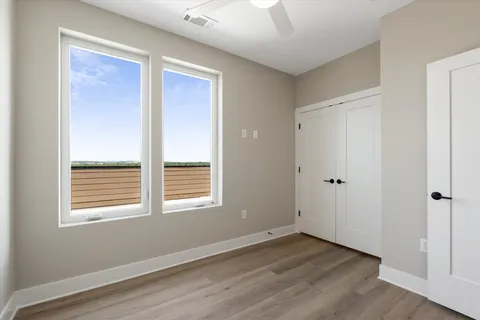 an empty room with wooden floor ceiling fan and windows