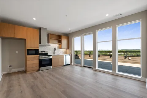 a kitchen with stainless steel appliances granite countertop a refrigerator oven a sink with wooden cabinets and wooden floor