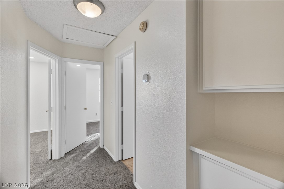 3156 Terrace View Drive Laughlin, NV 89029 - Photo 38 of 94 A well-lit corridor with soft carpeting leads to various rooms, promising comfort and accessibility.