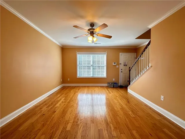an empty room with wooden floor fan and windows