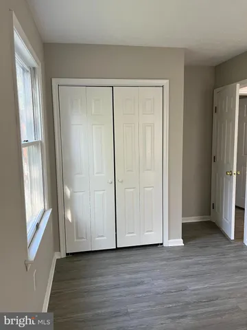 a view of an empty room with wooden floor and window