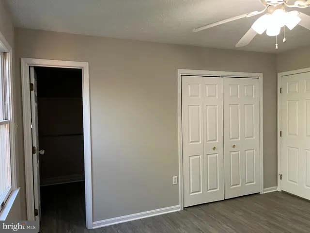 an empty room with wooden floor closet and windows