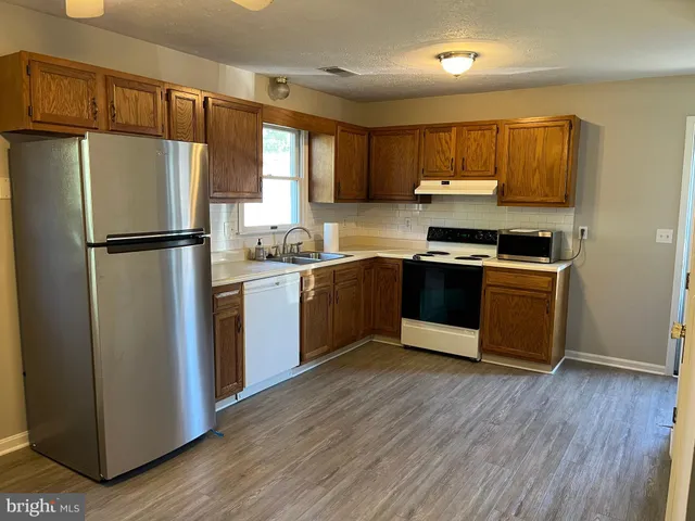 a kitchen with stainless steel appliances a refrigerator a sink a stove a microwave and wooden floors