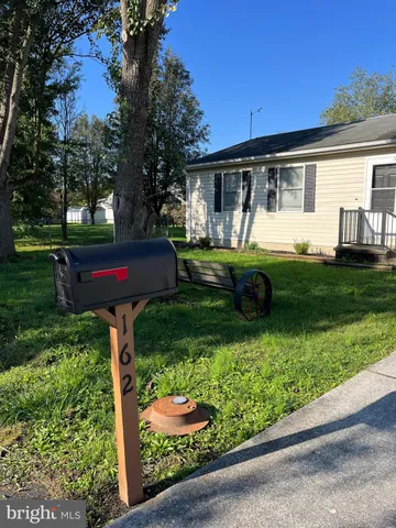 a front view of a house with garden and trees