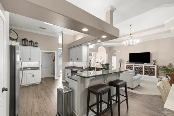 a living room with stainless steel appliances furniture a flat screen tv and kitchen view