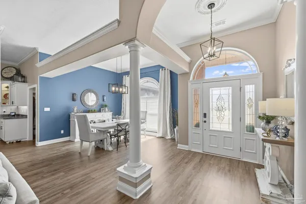 a dining room with wooden floor a chandelier a wooden table and chairs