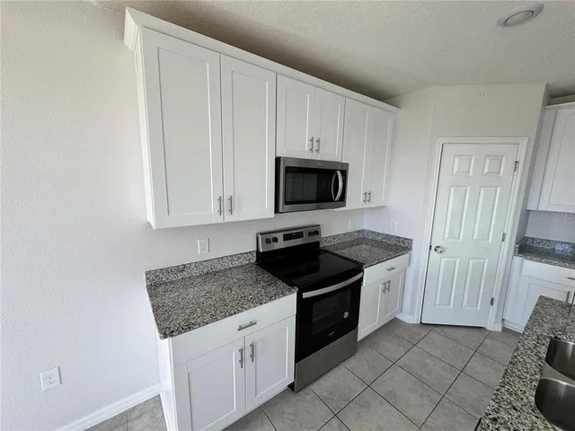 a kitchen with granite countertop white cabinets and black appliances