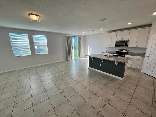 a large kitchen with kitchen island granite countertop a stove a sink a counter space and cabinets
