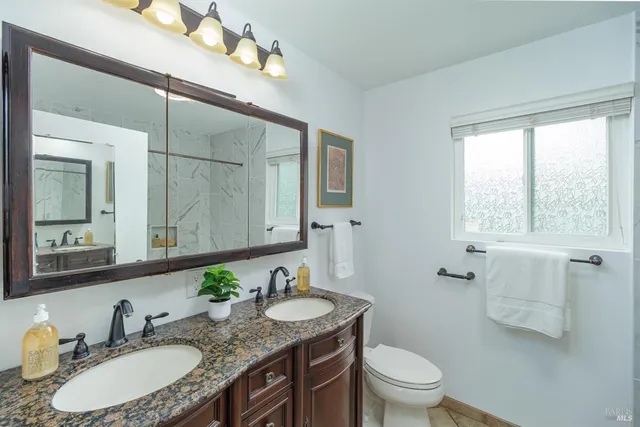 a bathroom with a granite countertop sink a toilet and a mirror