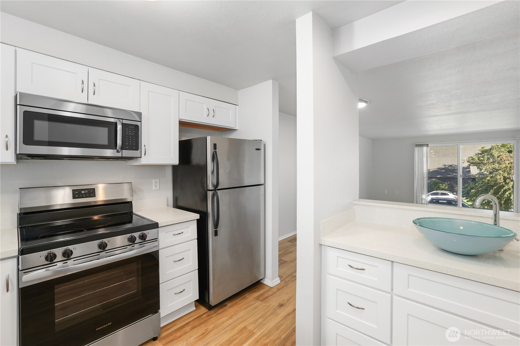 1010 North J Street, Unit 2 Tacoma, WA 98403 - Photo 11 of 29 a kitchen with white cabinets stainless steel appliances and wooden floor